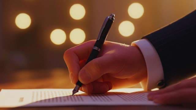 Businessman Signing Legal Document with Fountain Pen