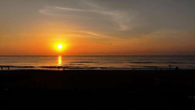 Beautiful Sunset Over Ocean Horizon with Silhouetted Beach Scene