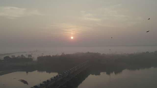 Misty Sunrise Over River Dam and Industrial Bridge
