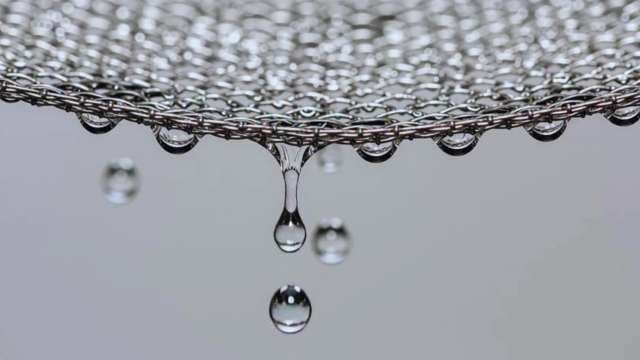 Macro Shot of Water Droplets Dripping From Metallic Mesh Filter