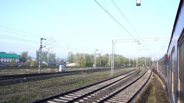 Side View of Train Traveling Through Scenic Rural Railway Tracks